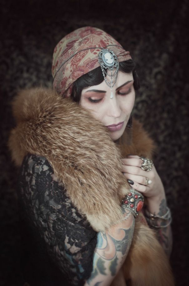 a woman with tattoos and a fur stole around her neck