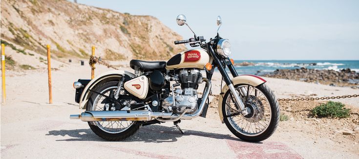 a motorcycle is parked on the side of the road by the beach and water in the background