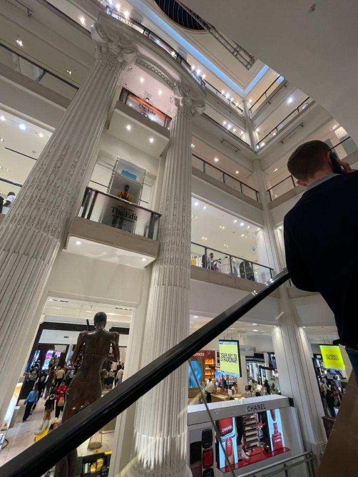 people are walking up and down the escalator in a shopping mall with columns