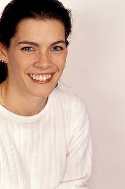 a smiling woman in a white sweater and gold hoop earrings is looking at the camera