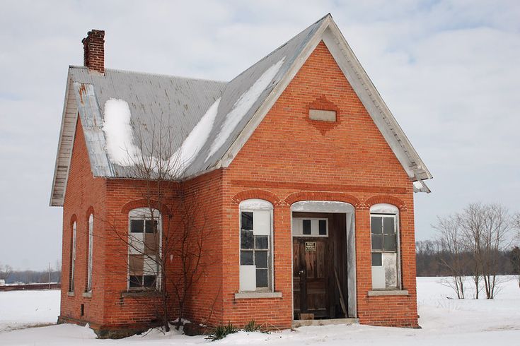 an old red brick house with snow on the ground