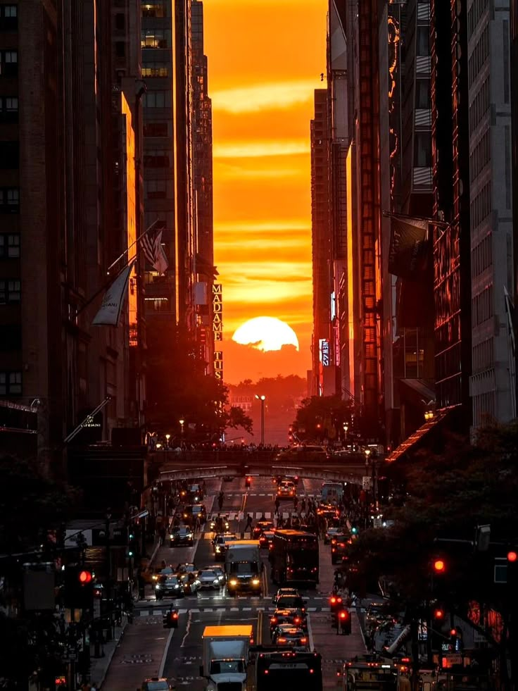 the sun is setting over a city street with tall buildings and traffic lights on both sides