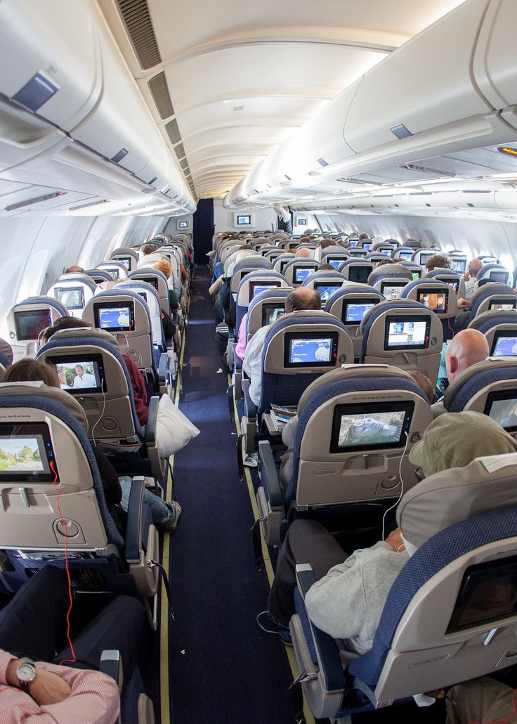 an airplane filled with lots of people sitting in it's seats and watching tv