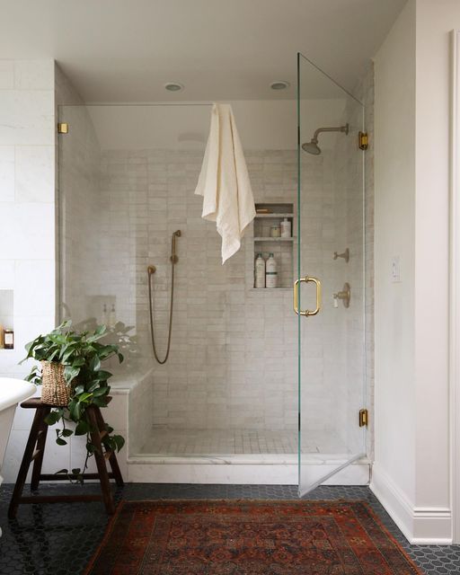 a bathroom with a walk in shower next to a bathtub and sink, along with a rug on the floor