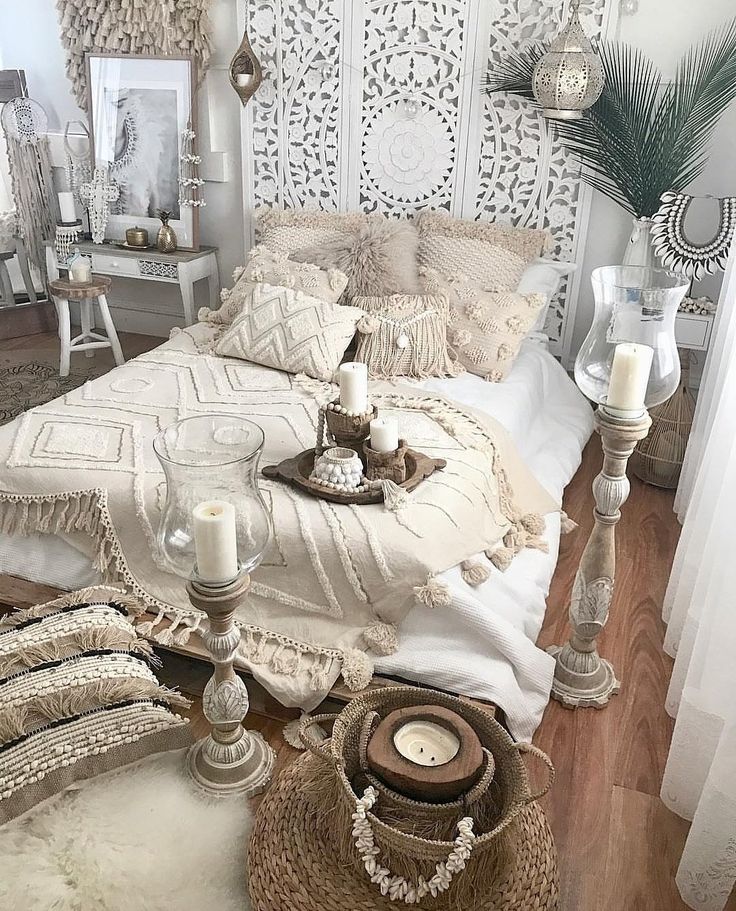 a bed with white sheets and pillows on top of it next to candles in baskets