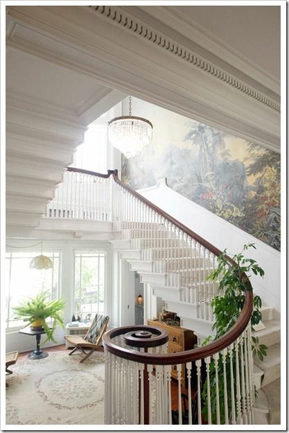 a staircase leading up to a living room with a painting on the wall behind it