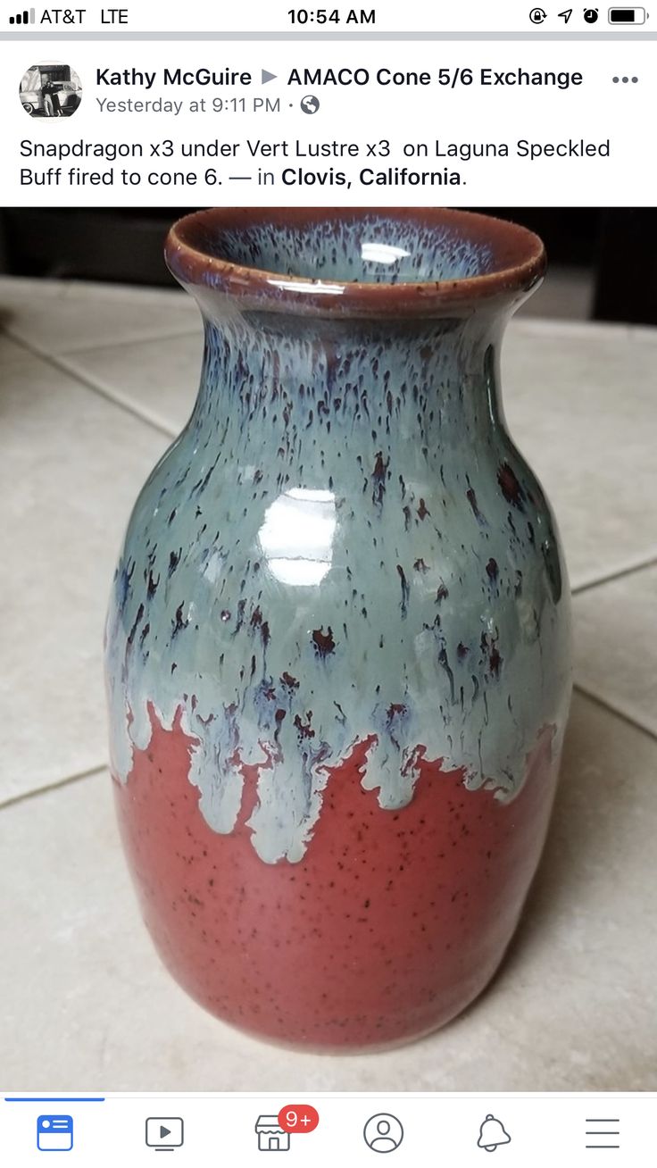 a blue and red vase sitting on top of a tile floor