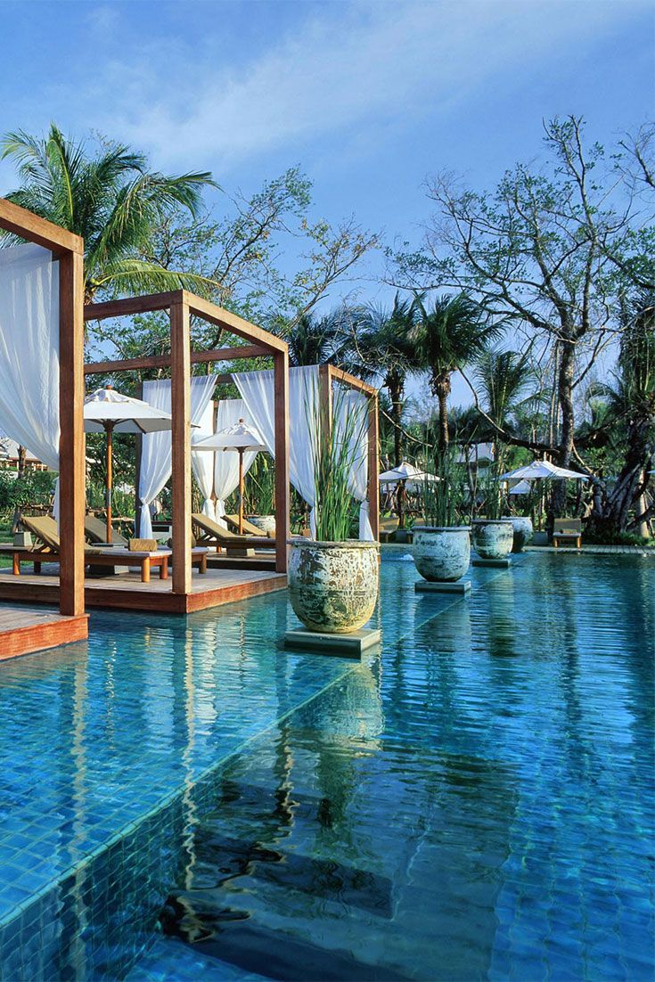 an outdoor swimming pool with lounge chairs and umbrellas