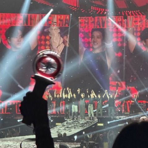 a group of people standing on top of a stage holding up their hands in the air