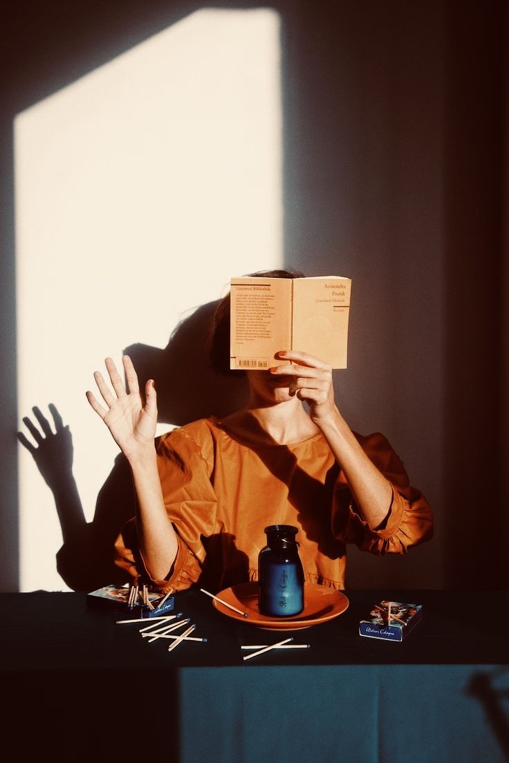 a woman sitting at a table with her hands up in the air while reading a book