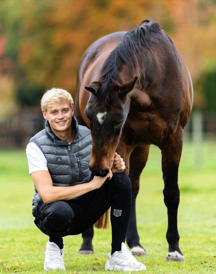 a man kneeling down next to a brown horse