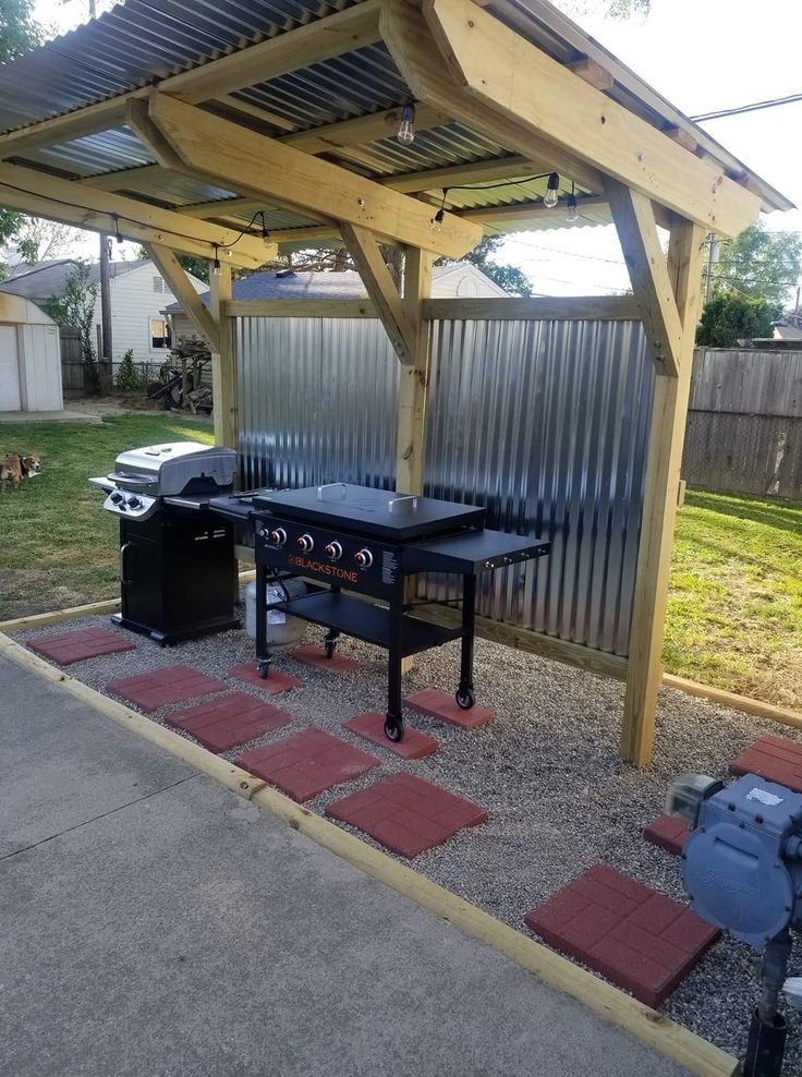 an outdoor bbq with grills and tables in the back yard