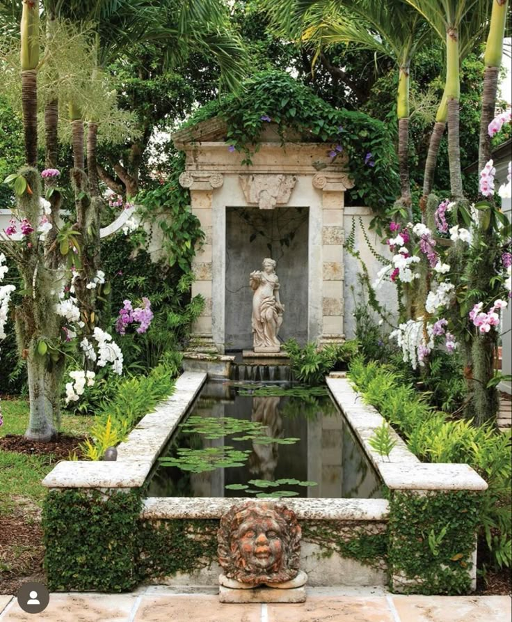 there is a fountain surrounded by flowers and trees