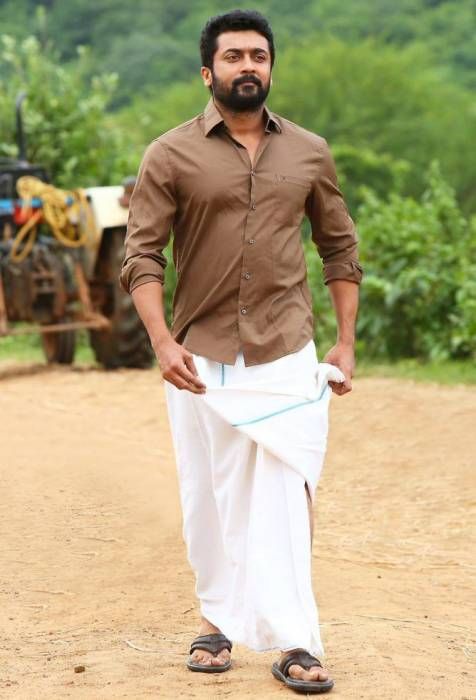 a man in brown shirt and white pants standing on dirt road