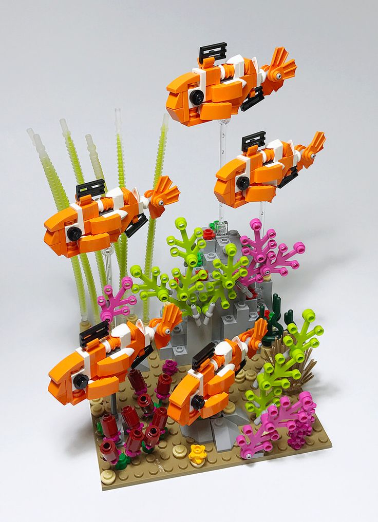 an orange and black lego boat is in the water with corals on it's sides