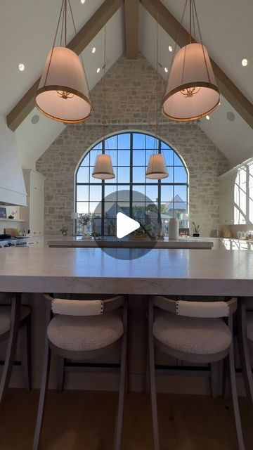 a large kitchen with an island in the center and three pendant lights hanging from the ceiling