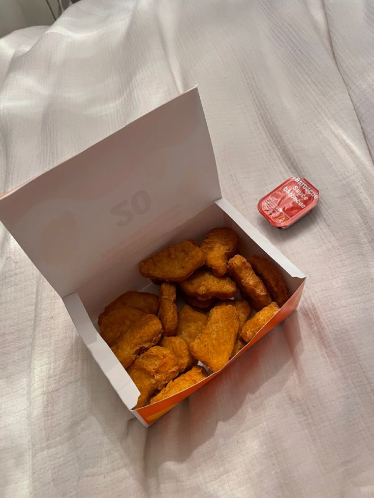 a box filled with fried food sitting on top of a bed