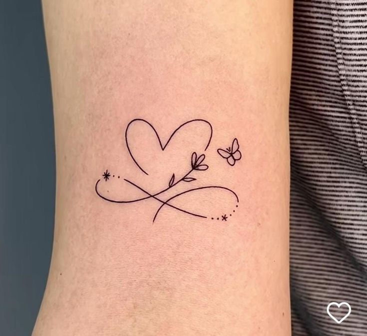 a small heart tattoo on the ankle with butterflies flying around it and stars in the sky