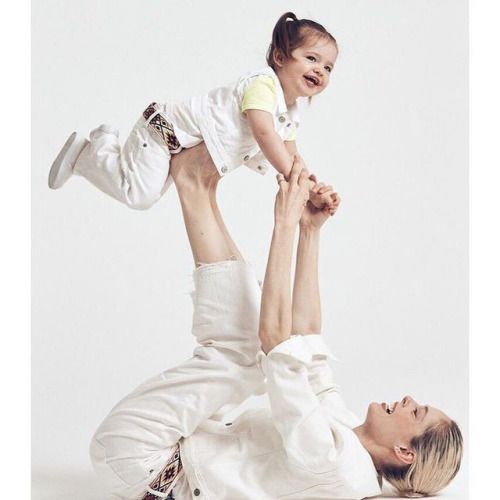 a woman holding a baby while laying on top of it's back in front of a white background