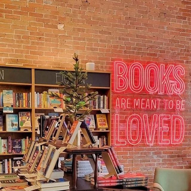 there is a book shelf with books on it and a neon sign in the background