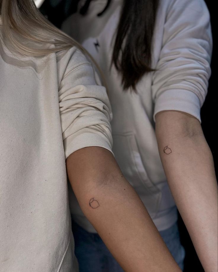 two women with matching tattoos on their arms