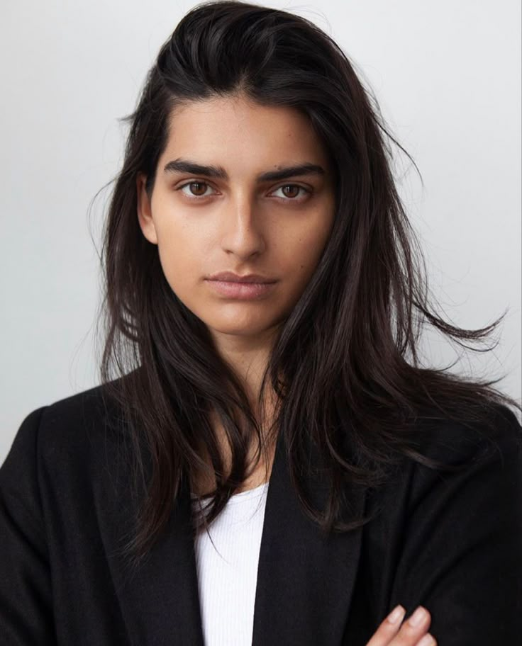 a woman with her arms crossed looking at the camera while wearing a black blazer