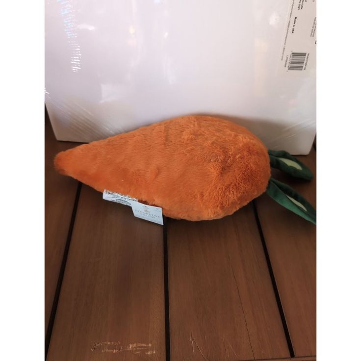 a stuffed carrot sitting on top of a wooden floor