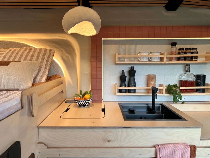 a kitchen area with sink, stove and shelves on the wall next to a bed