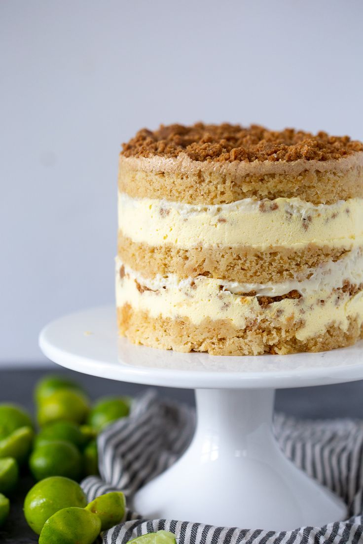 a cake with white frosting sitting on top of a table next to green apples