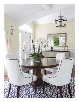 a dining room table with white chairs and flowers in a vase on top of it