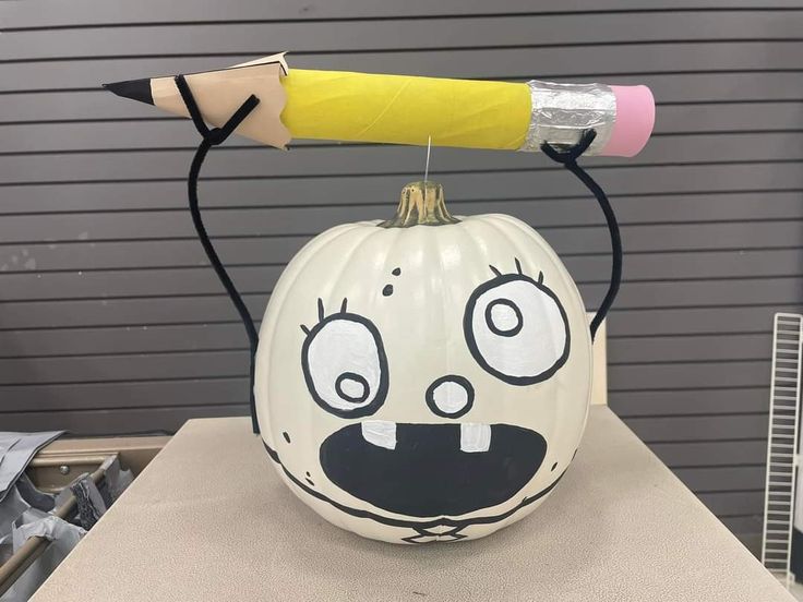 a painted pumpkin with a pencil sticking out of it's mouth and smiling face