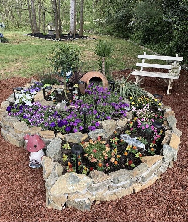 there is a garden in the middle of a rock circle with flowers and plants around it