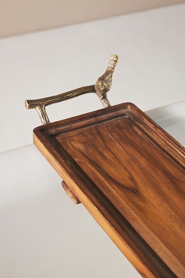 a small bird figurine sitting on top of a wooden desk next to a white wall