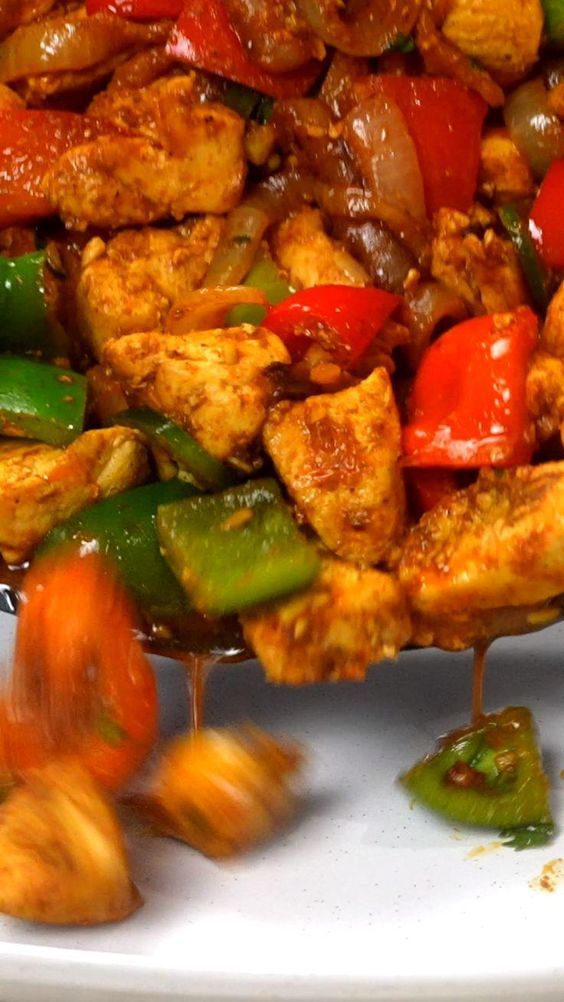 chicken and peppers are being cooked on a plate with chopsticks in the foreground