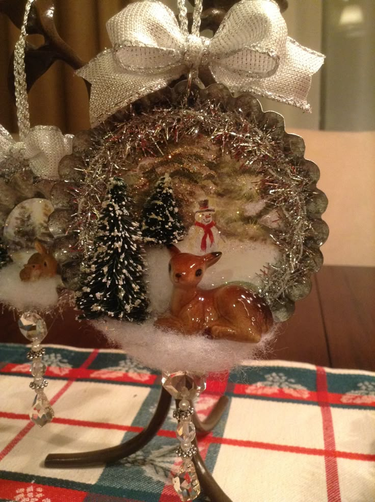 a glass ornament with deer and trees in it on top of a table