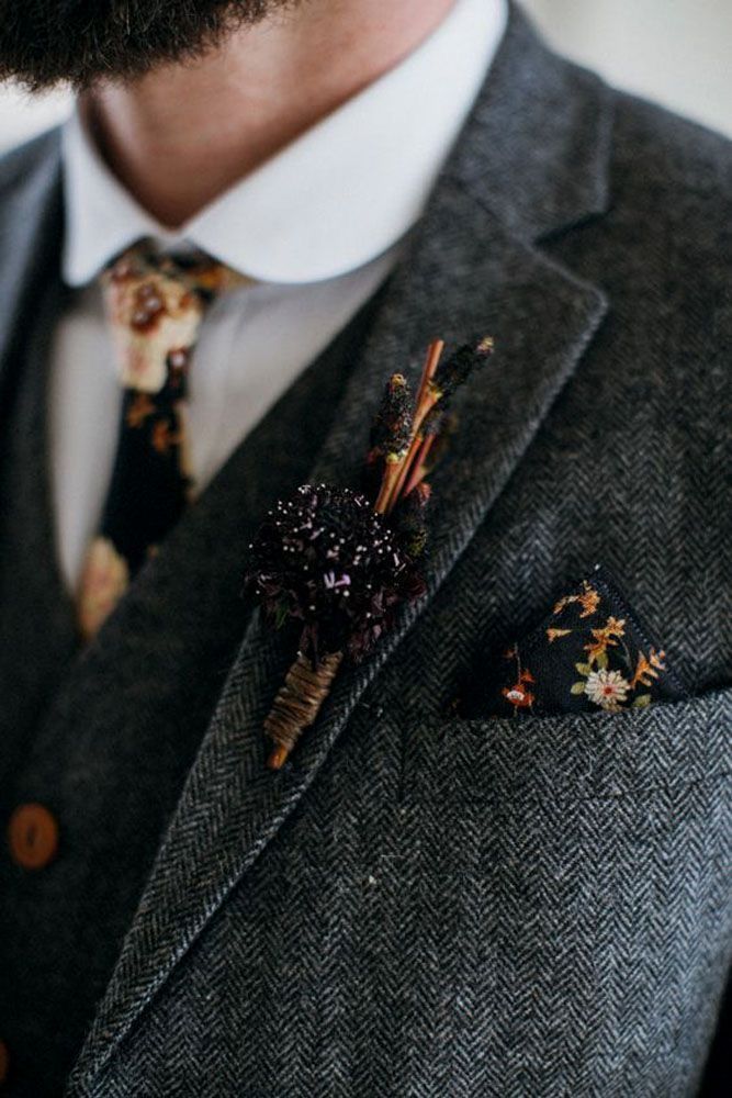 a man wearing a suit and tie with flowers on it's lapel pin