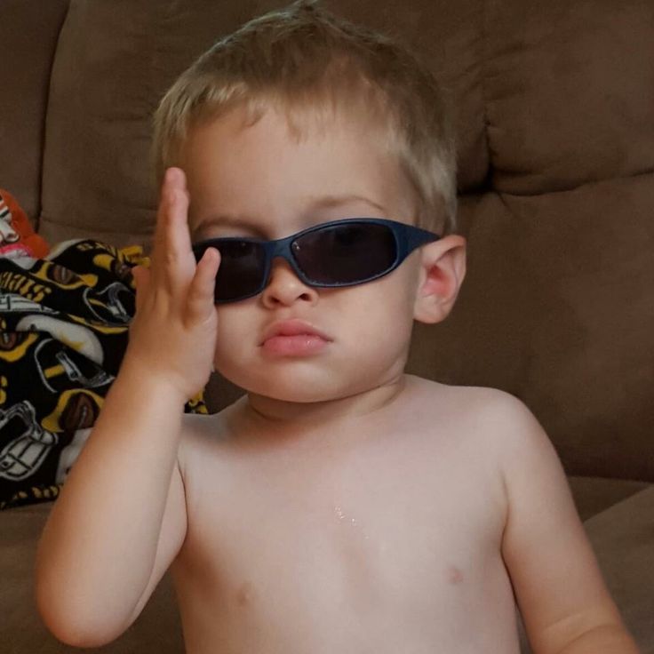 a young boy wearing sunglasses sitting on a couch