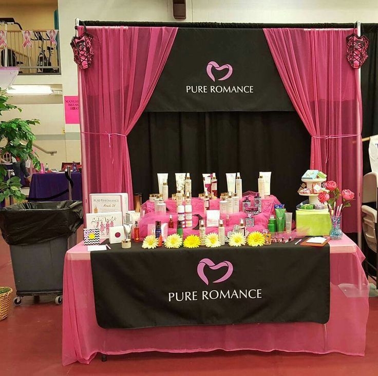 a table with pink and black decorations on it in front of a red curtained booth