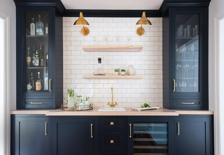 a kitchen with black cabinets and marble counter tops, white tile walls and flooring