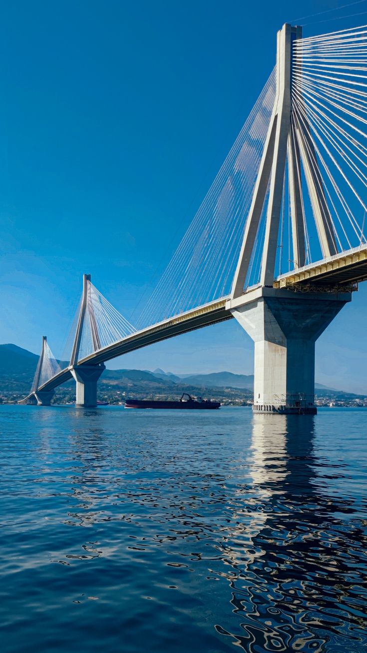 two large bridge spanning over the water on a sunny day with clear blue skies above