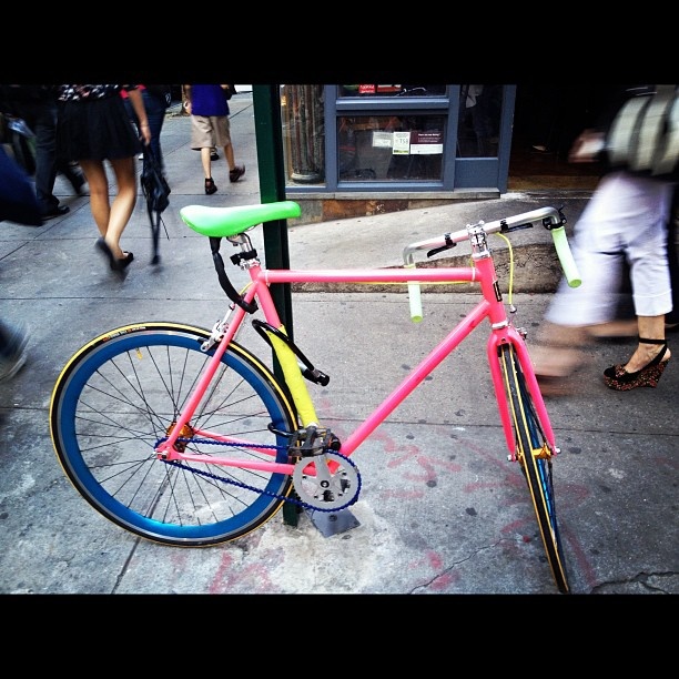 a pink and blue bike parked on the sidewalk