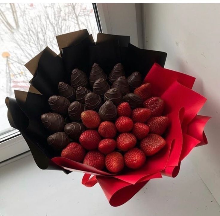 chocolate covered strawberries in a paper wrapper on a window sill by a window