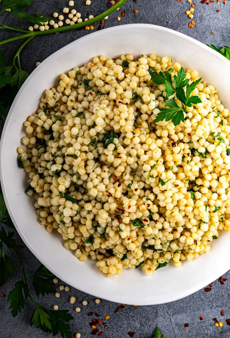 a white bowl filled with corn and garnished with parsley on the side