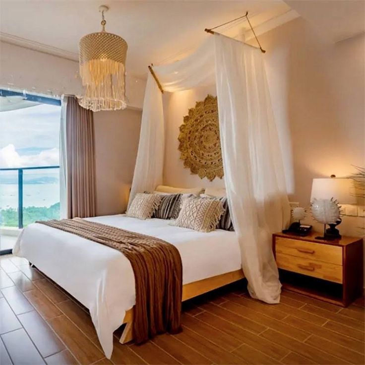 a bedroom with a bed, dresser and large window overlooking the ocean in front of it