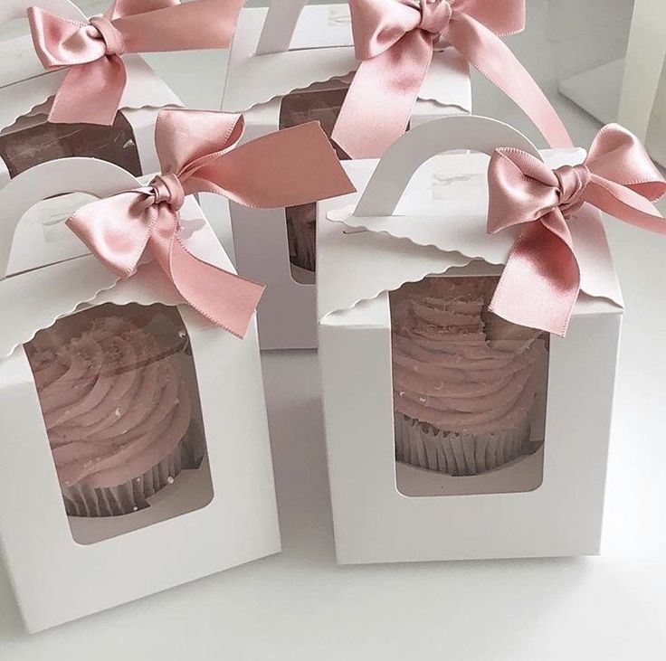 six cupcakes with pink bows in white boxes