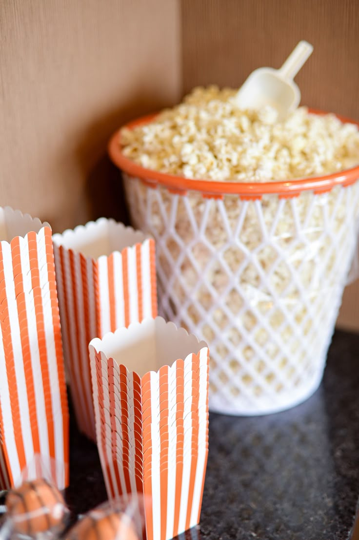 popcorn in striped paper bags next to an orange and white basket