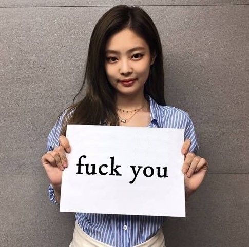 a woman holding up a sign with the words f k you on it in front of her