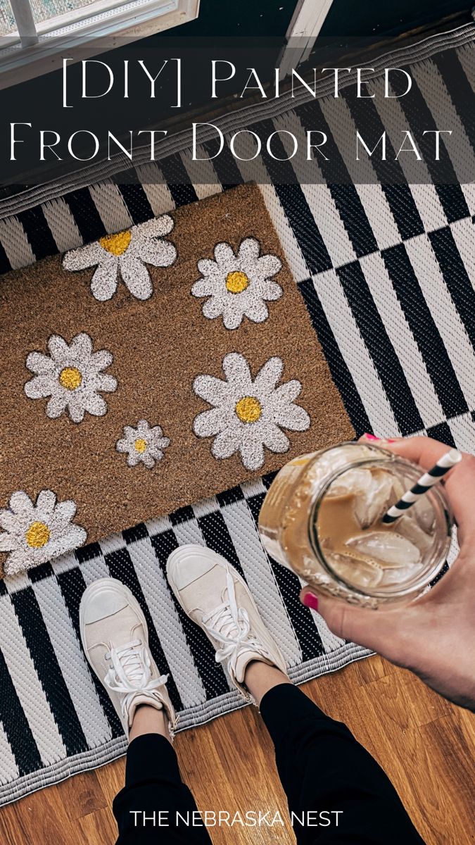 someone is painting the front door mat with white flowers on black and white striped rug