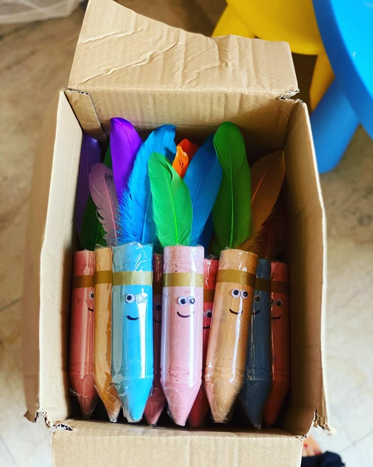 a cardboard box filled with different colored pencils and some smiling faces drawn on them