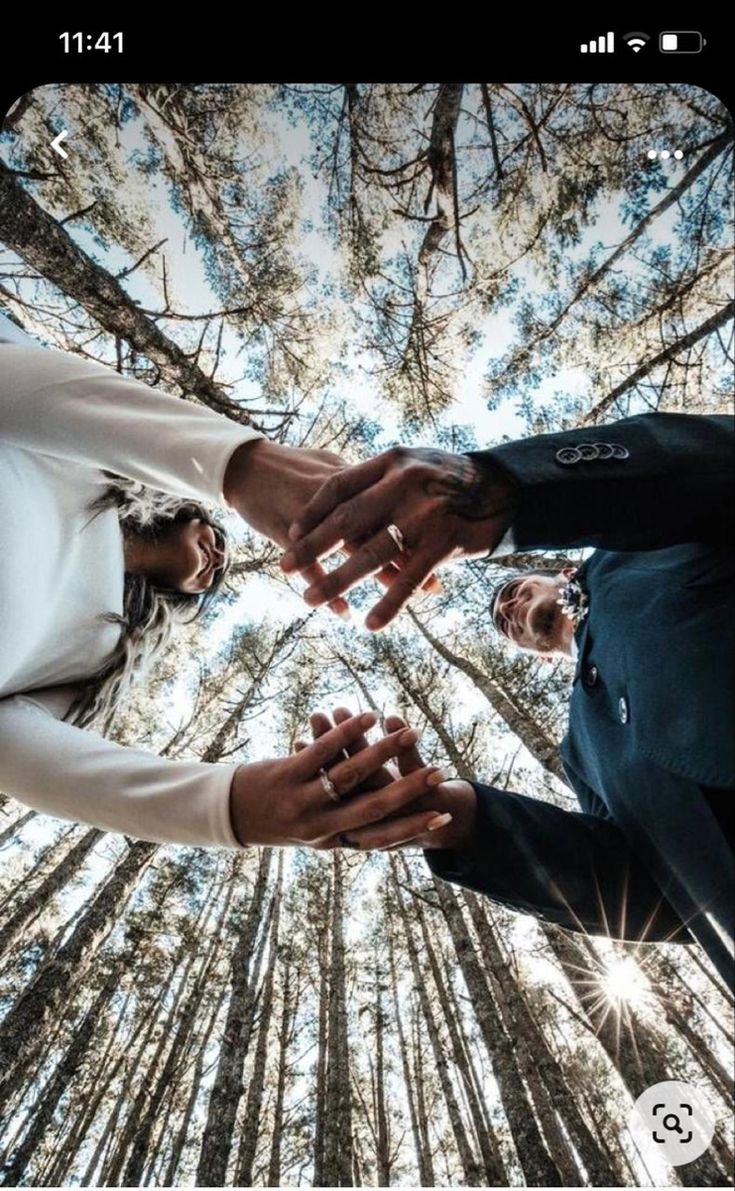 two people holding hands in the middle of a forest